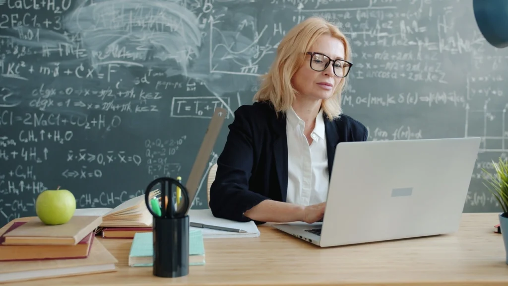 Nauczycielka pracująca przy laptopie w klasie pełnej szkolnych inspiracji i pomysłów na Dzień Nauczyciela.