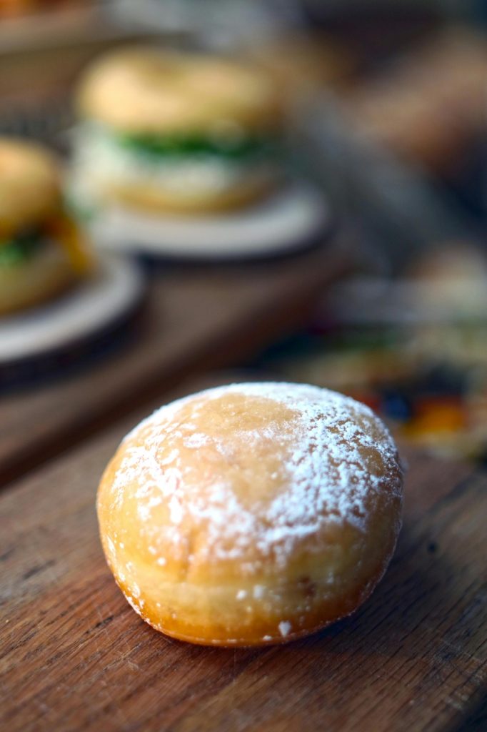 Pączek z cukrem pudrem na drewnianym stole – tradycyjny wypiek na Tłusty Czwartek.
