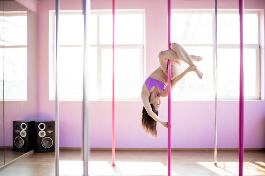 Pole Dance - kobieta zawieszona na rurce w akrobacji