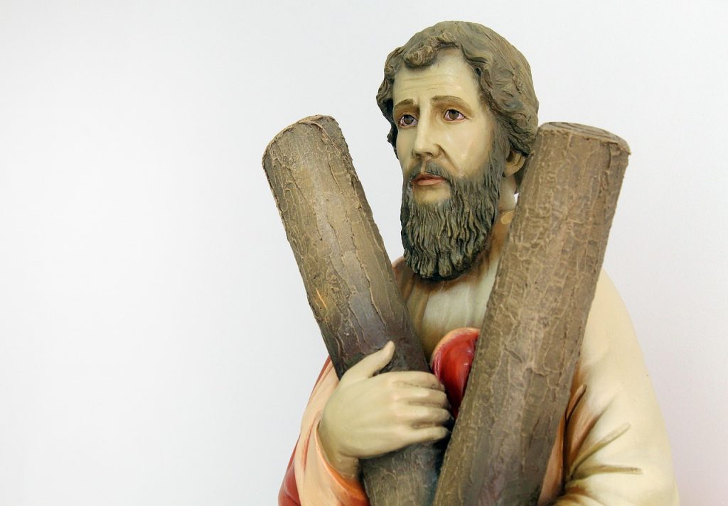 Figura św. Andrzeja trzymającego dwa kawałki drewna – symboliczne przedstawienie Andrzejek na jasnym tle.