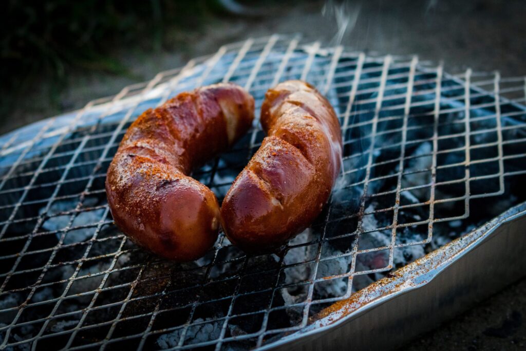 Majówka 2026 grill na świeżym powietrzu, pieczone kiełbaski na ruszcie podczas długiego weekendu majowego, klasyczny pomysł na relaks i wspólne spędzanie czasu w Polsce.