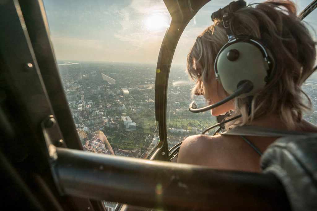 Kobieta leci helikopterem i podziwia miasto w dole