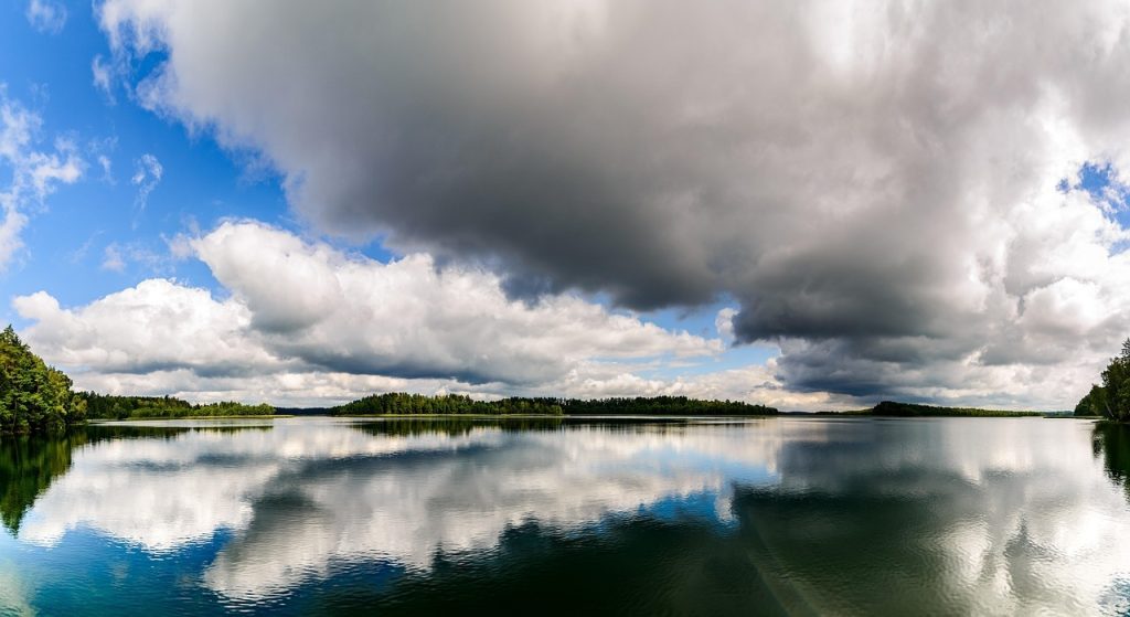 Jezioro na Mazurach, duże chmury nad nim, weekend na Mazurach z dziećmi.
