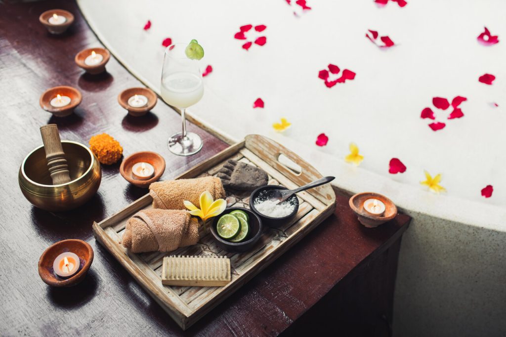 Zestaw spa z ręcznikami, świecami i drinkiem obok wanny z płatkami kwiatów – luksusowy relaks w hotelu, idealny przykład tego, ile kosztuje nocleg w hotelu z atrakcjami wellness.