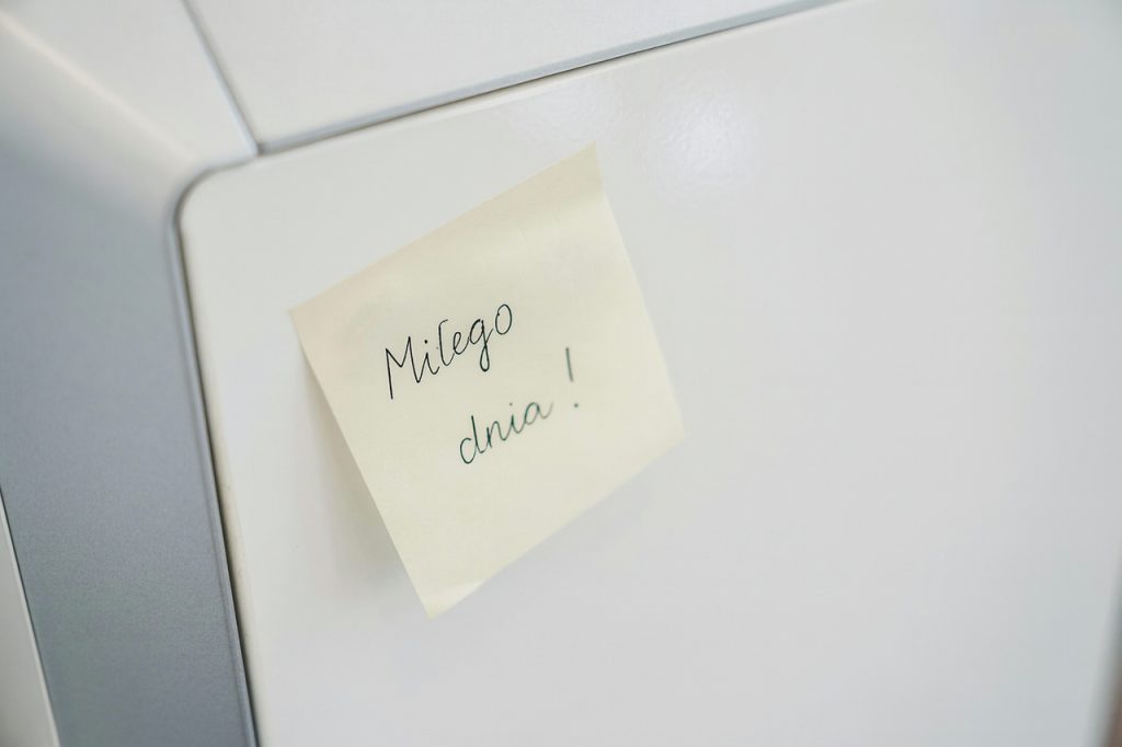 Żółta karteczka samoprzylepna z napisem „Miłego dnia!” przyklejona na lodówce – prosty gest życzliwości i uśmiechu z okazji Dnia Życzliwości i Pozdrowień.