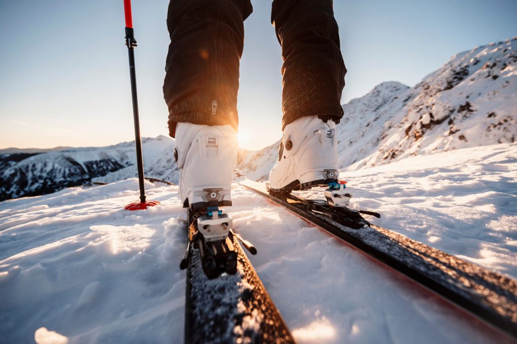 Ferie zimowe 2026 – narciarz stojący na nartach na ośnieżonym stoku w górach.