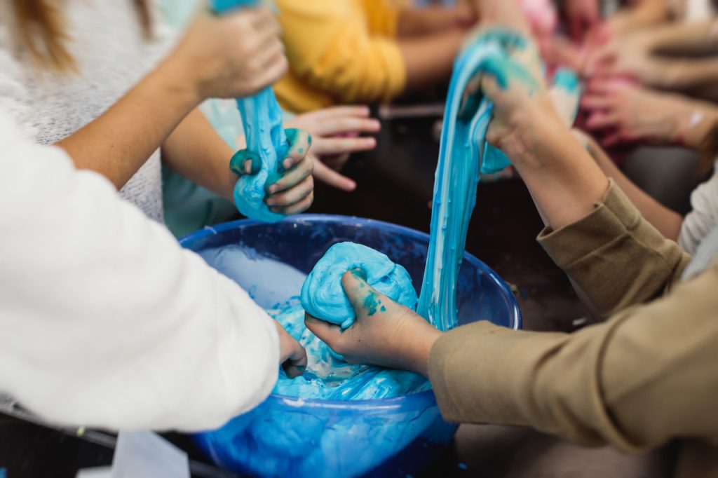 Dzień Dziecka 1 czerwca, dzieci bawiące się niebieskim slime podczas kreatywnych warsztatów.