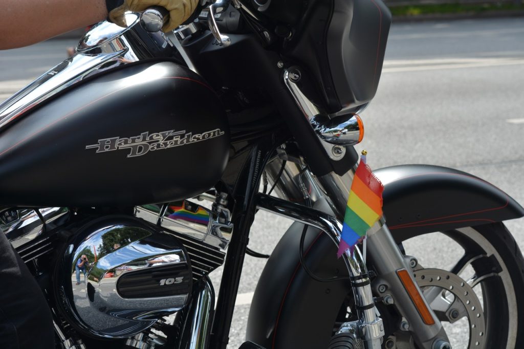 Harley-Davidson z tęczową flagą LGBT przy siodełku w kontekście Pride Month i Miesiąca Dumy.