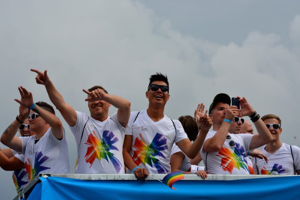 Uczestnicy parady równości w białych koszulkach z tęczowym motywem podczas obchodów Pride Month.