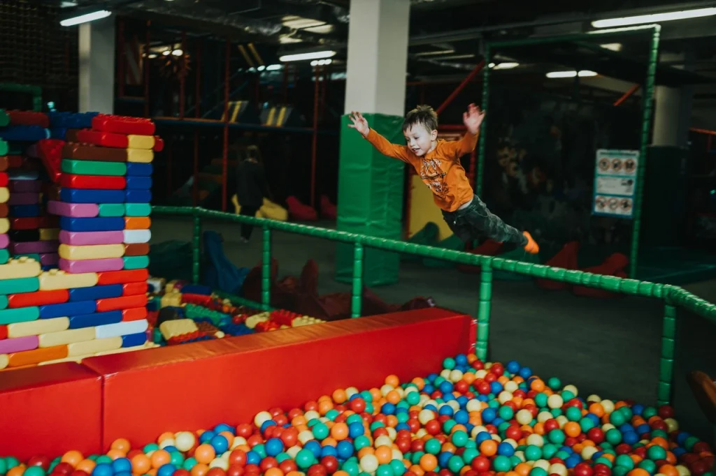 Zabawa w parku trampolin z basenem z gąbkami jako pomysł na prezent do 30 zł.
